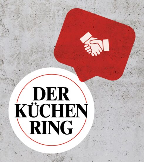 Betonhintergrund mit Der Küchenring Logo und Handschüttel-Icon auf rotem Layer