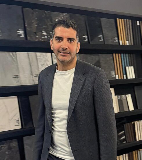 Foto von Alpay Keskin vor einer Musterwand in der Ausstellung