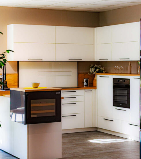 Weiße U-Küche mit Weinkühlschrank und Holzarbeitsplatte.