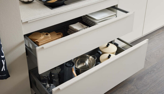 Offene Küchenschubladen mit Kochgeschirr, Schneidebrettern und Töpfen – durchdachte Aufbewahrung „Made in Germany“.