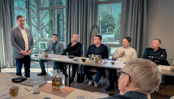 Marcus Roth steht vor einer sitzenden Tagungsgruppe