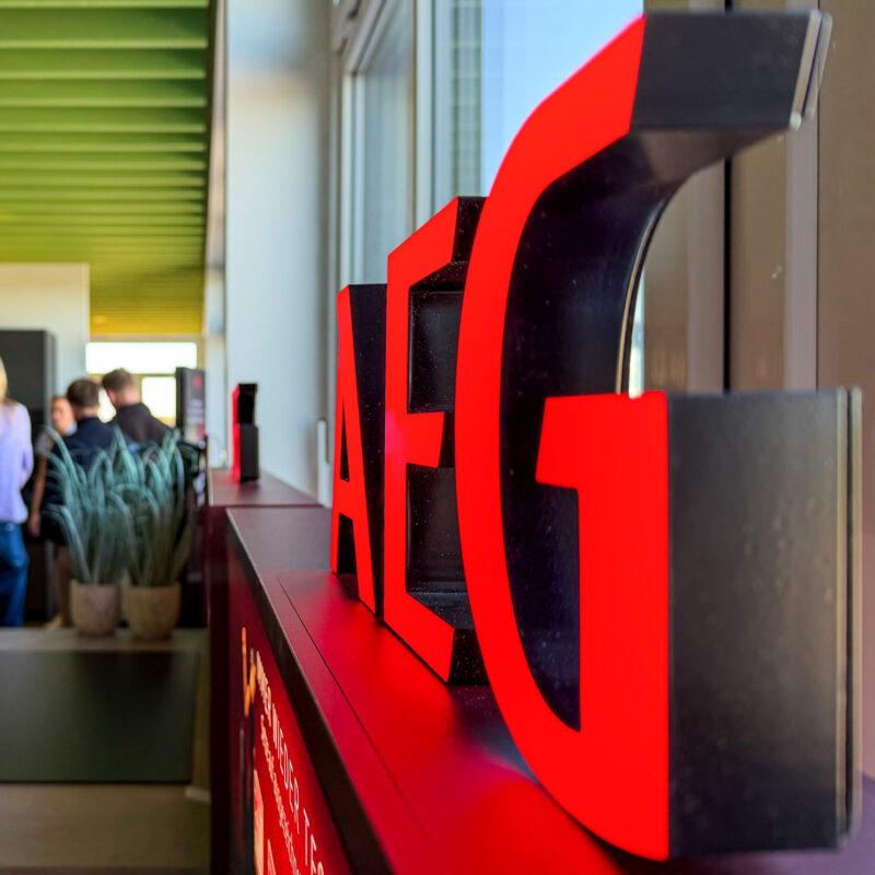 Leuchtendes AEG-Logo in Rot auf einer Theke in einem modernen Innenraum.