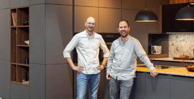 Zwei Küchenexperten stehen in moderner Ausstellungsküche im Küchenstudio