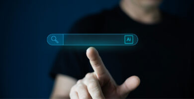 KI-Suche: Person bedient digitale Suchleiste mit KI-Symbol auf einem Bildschirm.