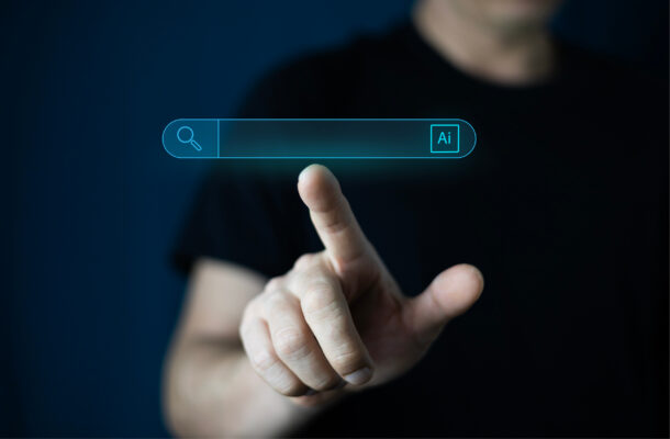 KI-Suche: Person bedient digitale Suchleiste mit KI-Symbol auf einem Bildschirm.